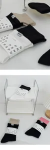 Detail shot of color-blocked crew socks with branded paper band packaging and woven labels on clean shelf.
