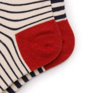 Gros plan de chaussettes rayées en coton avec talon rouge contrasté, texture tricot douce et confort.