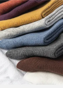 Close up of colorful knit socks stacked neatly, showing soft ribbed texture and quality fabric.