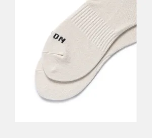 Close-up detail of off-white cotton mid-calf socks with knit letter design, breathable.