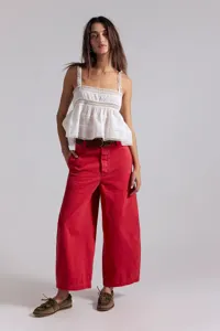 Elegantes Damen weißes Spitzen-Cami-Top kombiniert mit roten weiten Jeans und einem Gürtel.