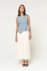 Close-up detail view of the fashionable striped asymmetric vest and elegant long cream skirt.