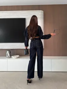 Detailed view of dark denim long-sleeve crop top and wide-leg trousers with contrast stitching.