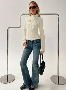 Detail view of a stylish slim-fit utility jacket paired with flared denim jeans in studio.