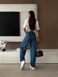 Detailed lifestyle shot of blue wide-leg denim jeans paired with casual white top.