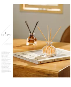 Detailed shot of glass reed diffuser bottle with sticks on wooden table for home fragrance.