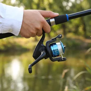 Detailed view of telescopic fishing rod and spinning reel set outdoors with blue metal spool.