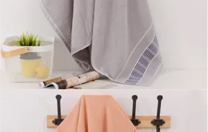 Detailed shot of pure cotton bath towel in home lifestyle setting with minimalist hooks and basket.
