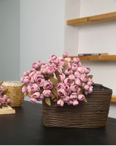 Nahaufnahme eines künstlichen Teerosen-Blumenstraußes im geflochtenen Korb, Deko.