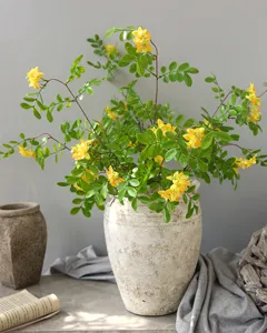 Artificial yellow bean locust flower detail scene home decor floral arrangement in rustic vase.