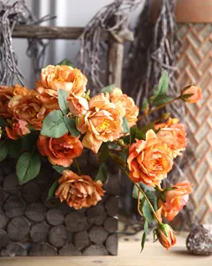 Primo piano di finte peonie vintage arancioni con foglie verdi per la vostra casa.