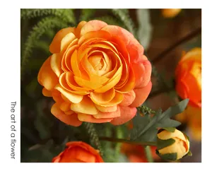 Close up view of artificial ranunculus flower, orange silk floral decor detail for home table setup.