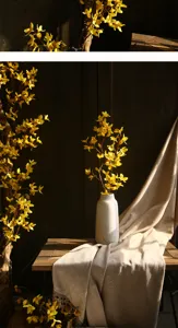 Gros plan d'une branche de forsythia jaune artificielle dans un vase blanc pour beau decor interieur.