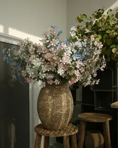 Detailaufnahme künstlicher Wildblumen in rustikaler goldener Vase, ideal für gemütliche Wohnkultur.