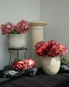 Vista dettagliata di composizione floreale di ortensie artificiali con vasi texturizzati e decori.