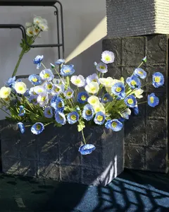 Close-up of blue white artificial poppy bouquet in dark rustic planter with velvet petals.