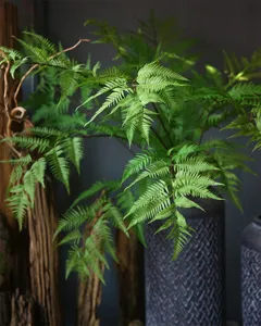 Artificial fern leaf detail shot, realistic green foliage arrangement for interior decor.