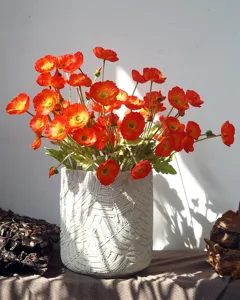 Detail shot of artificial poppy bouquet in textured ceramic vase, pastoral home decor style.