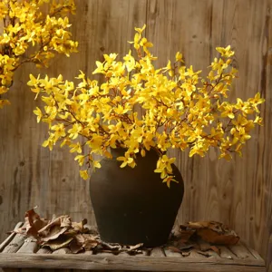 Branches de fleurs jaunes de forsythia artificielles dans un vase en poterie noire