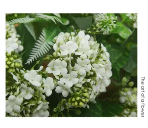 Close-up detail of artificial white hydrangea flower with lush green leaves for decor.