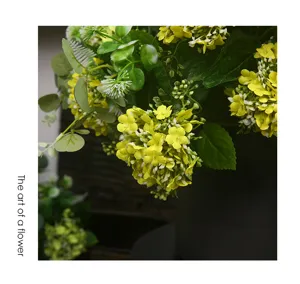 Detailed close-up of artificial yellow snowball flowers in a dark vase, perfect for home decor.