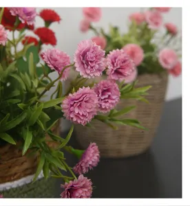 Artificial small carnation flower arrangement detail, pink and red faux floral decor for home table.