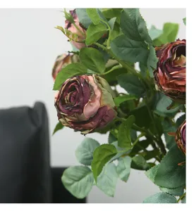 Detailed close-up of artificial vintage burnt-edge roses with realistic green leaves.