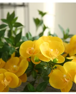 Close-up shot of yellow artificial phalaenopsis flower branch showing realistic petal texture.