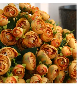 Detailed close-up of orange artificial camellia flower bouquet, vibrant home decor accessory.