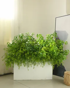 Detailed view of artificial fern and foliage arrangement in white planter for indoor decor.