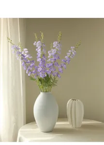 Detailed view of artificial purple delphinium flowers arranged nicely in a ceramic vase.