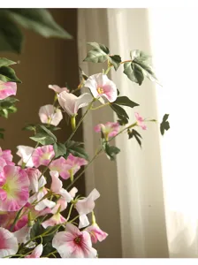 Detail shot of artificial morning glory flower, pink and white petals, realistic indoor decor.