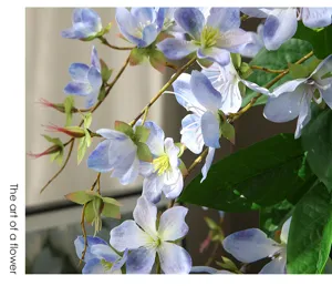 Detailaufnahme künstlicher hängender Jasminblüten mit zarten blauen Blumen und grünen Blättern.