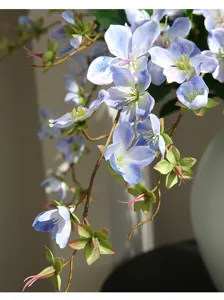 Nahaufnahme künstlicher hellblauer Jasmin-Blütenzweig mit grünen Knospen und braunem Stiel.
