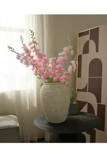 Detailed view of artificial pink delphinium flowers in a vintage ceramic vase for home decor.