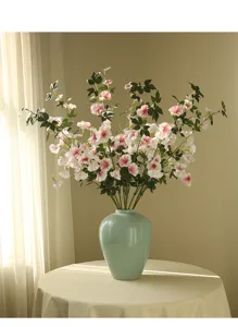 Artificial morning glory flowers in blue ceramic vase, indoor pastoral decor detail shot.