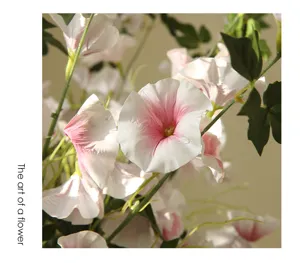 Close-up detail of artificial pink and white morning glory flower with realistic green stems.