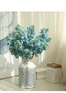 Close-up detail of artificial blue lilac flowers in patterned vase for home decor setup.