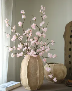 Artificial cherry blossom branches with rustic vases for home table decoration and elegant room styling.