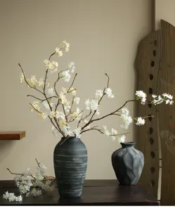 Detail view of artificial snow ball flower branch in ceramic vase for home decor.