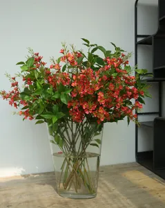 Exquisite artificial wintersweet flower arrangement in a clear glass vase for home decor.