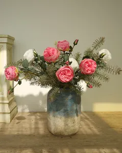 Primo piano di bouquet di rose artificiali Austin con aghi di pino in vaso di ceramica.