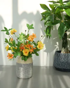 Dettaglio ravvicinato di bouquet di fiori artificiali con vaso in ceramica e margherite.