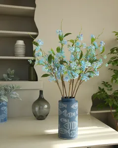 Detailed view of artificial blue alyssum flowers in a blue decorative fish pattern vase.