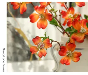 Detailed view of artificial orange dogwood flower arrangement in ceramic vase for home decor
