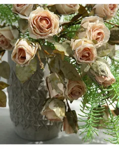Detailopname van kunstmatige vintage rozen met verbrande randen en groen blad.