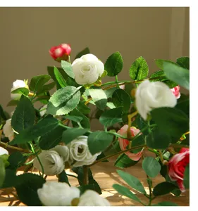 Primer plano detallado de guirnalda de rosas artificiales con flores blancas y hojas verdes.