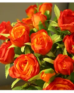 Detailed close-up shot of artificial orange silk rose flowers, perfect for home decor.