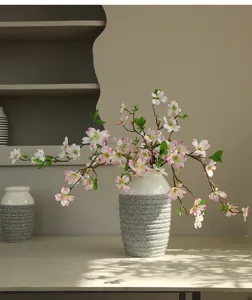 Detail view of artificial dogwood flower branches in textured ceramic vase for indoor home decor
