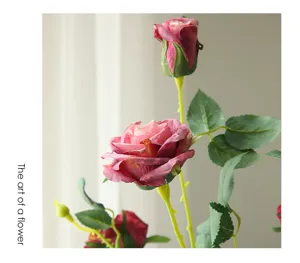 Close-up detail of artificial retro burnt-edge rose flower branch with green leaves for decor.